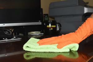 Top of a counter being wiped down by a gloved hand using a towel.